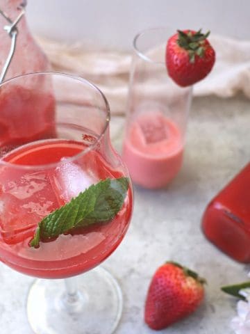 strawberry liqueur drink in a glass on ice with strawberry and flour decoration