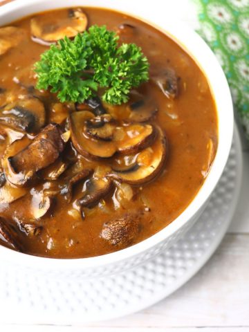 Jager schnitzel gravy in a white bowl on a plate.