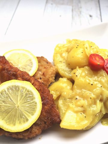 Cold swabian potato salad with cherry tomato garnish.