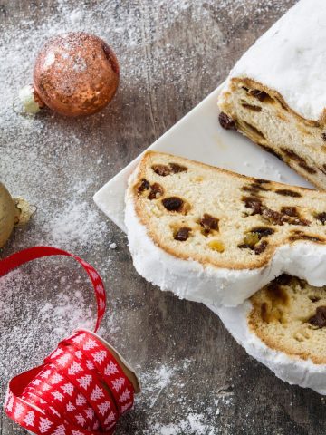 Traditional German Christmas desserts on baking sheets in winter greenery decoration. Stollen on the left side and honey cake and pie on the right side.