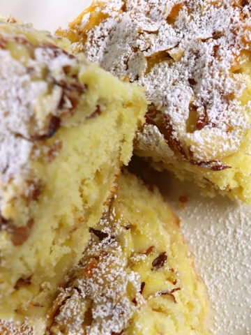 Slices of German butter cake topped with powdered sugar on a white plate.
