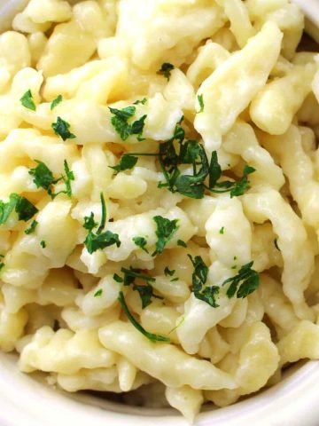 Spaetzle with parsley garnish in a white bowl.