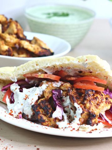German chicken doner on a white plate. Chicken doner meat on a white plate and doner sauces in glass bowls in the background.
