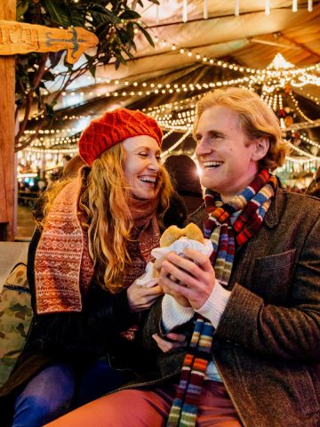 Young German couple eating food at the Christmas market.