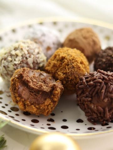 Assorted Rumkugeln aka German rum balls on a white and gold Christmas plate.